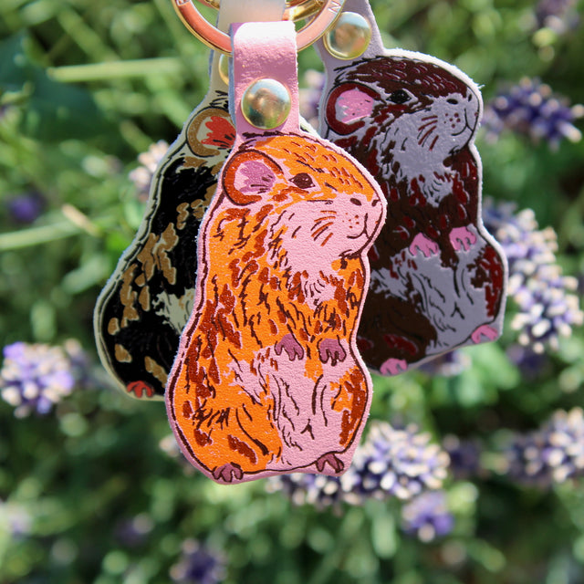 Three guinea pig leather keyrings with a gold plated ring. Handmade in Cambridge using hot foil.