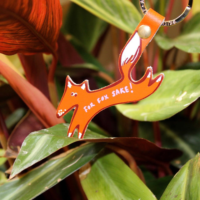 Orange fox-shaped keychain with 'For Fox Sake!' text on green leaves