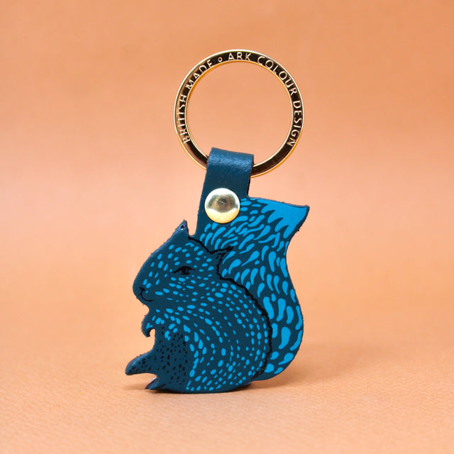 A dark turquoise squirrel key ring design on a gold plated ring with 'nuts' on the reverse.